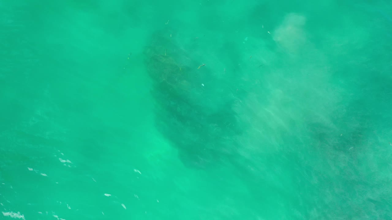 Turquoise-green water over a darker underwater patch.