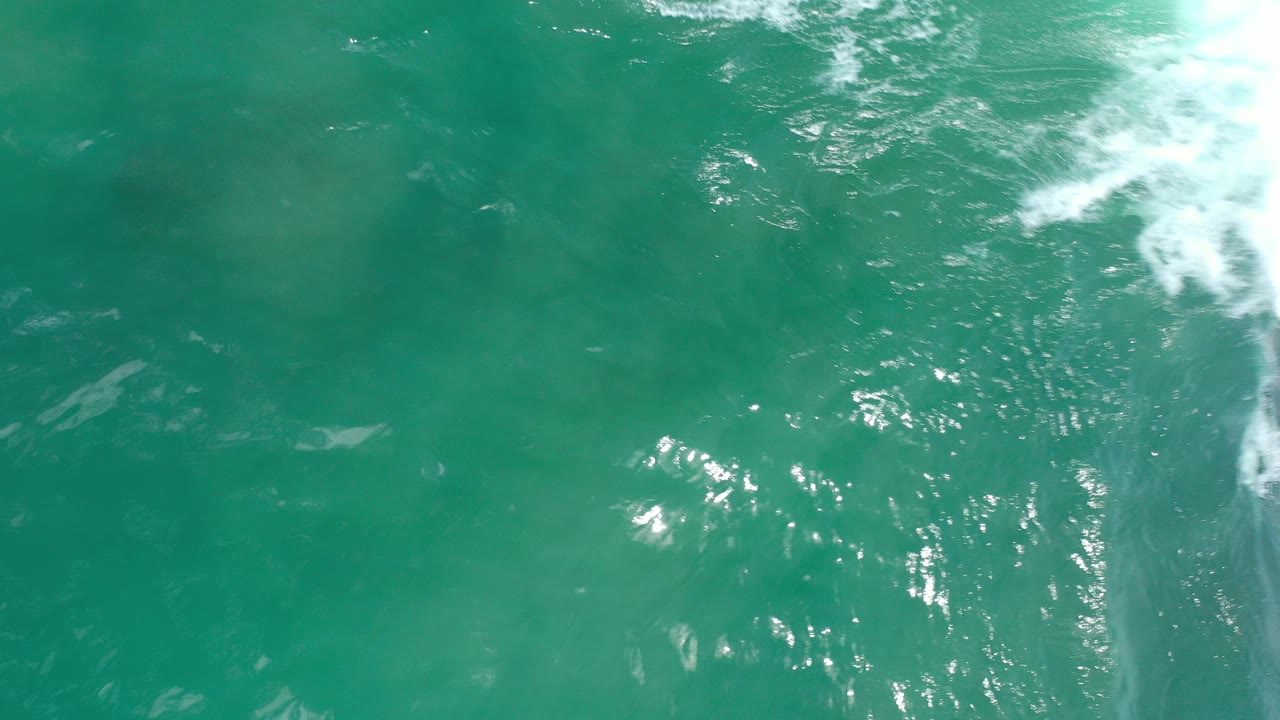 Aquamarine ocean water with white foam near the upper right edge.