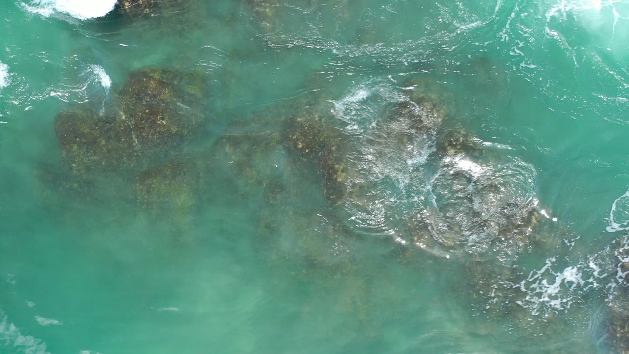 Turquoise ocean water over dark coastal rocks