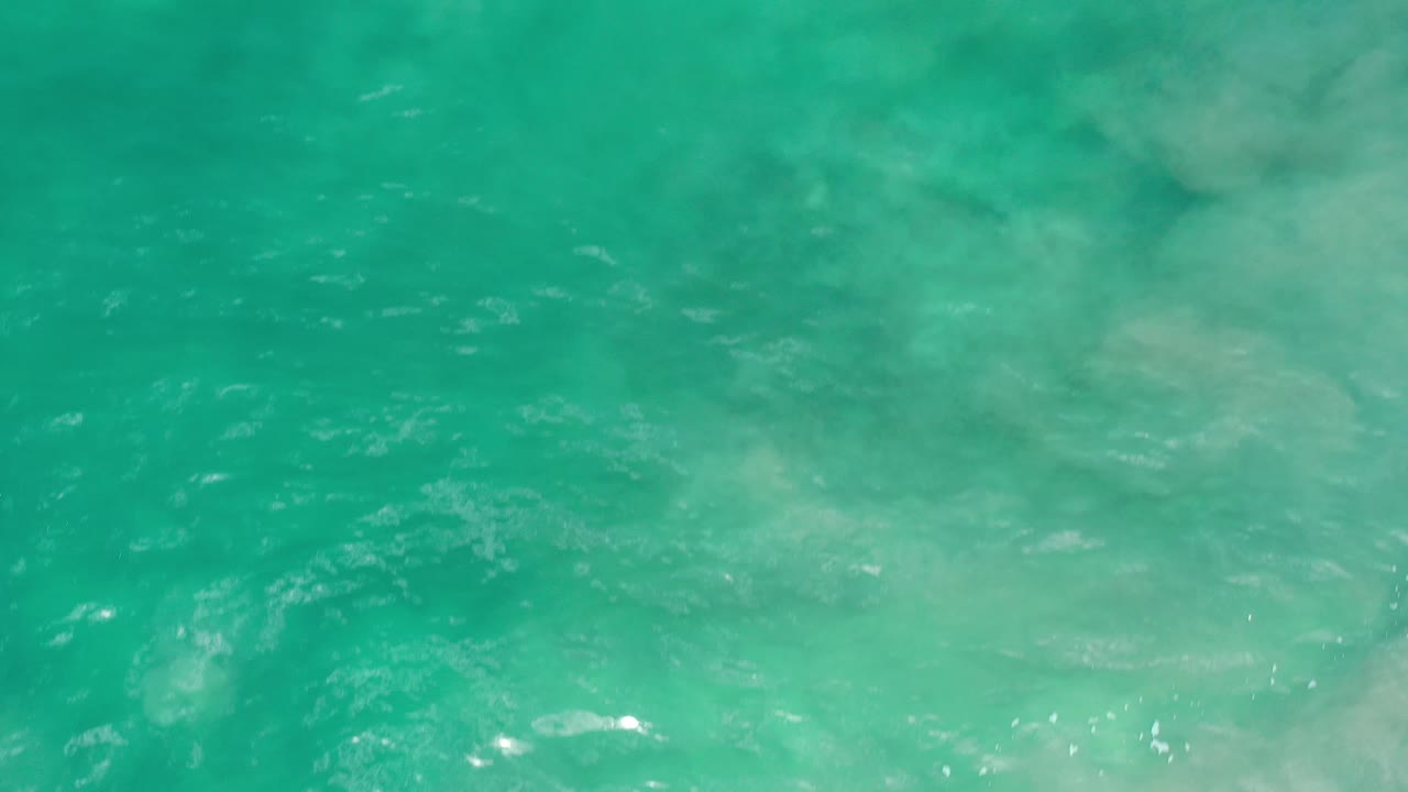 Turquoise water surface with cloudy green areas and fine ripples.