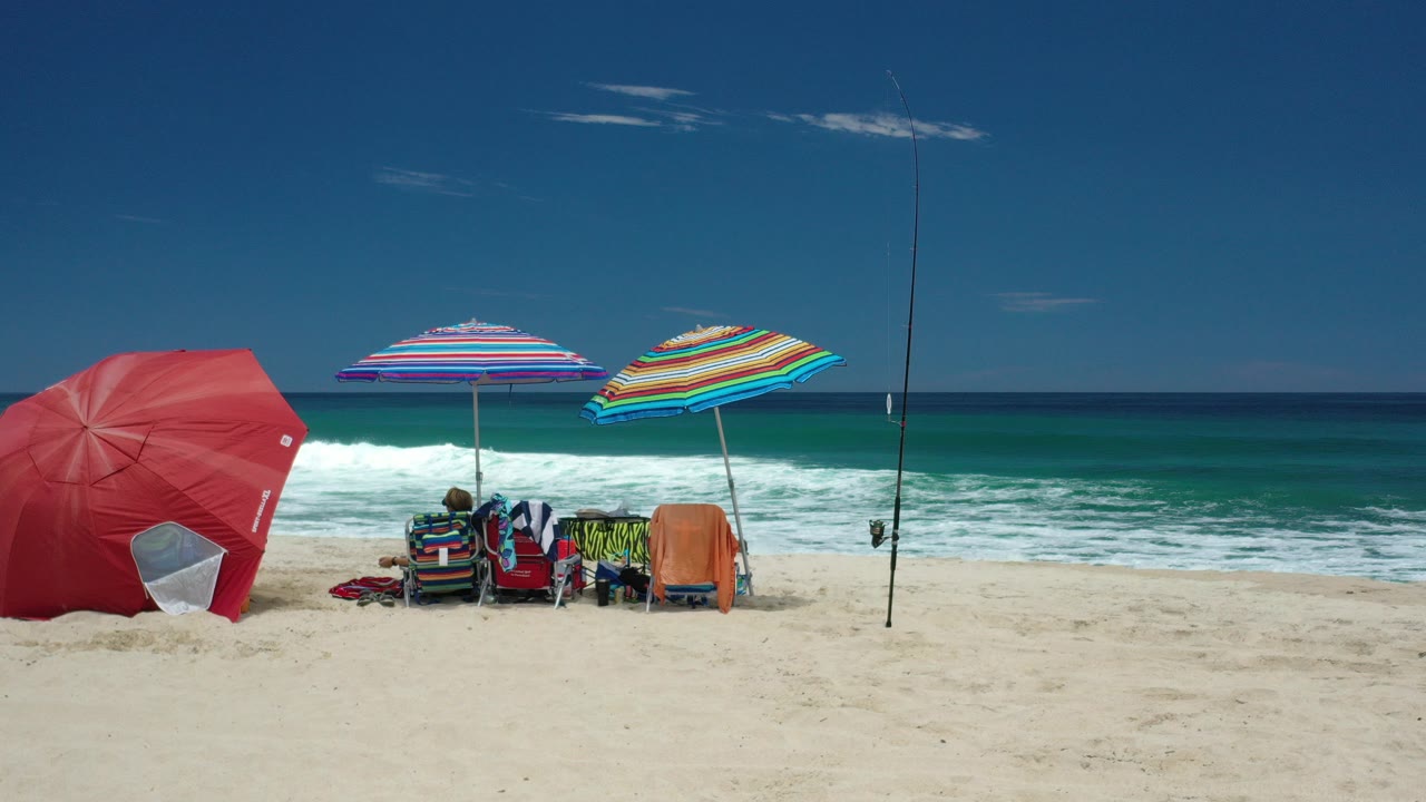 Beach umbrellas and chairs beside breaking surf