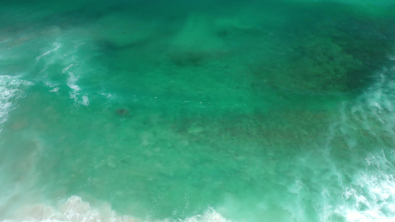 Turquoise surf with white foam bands and a darker water patch.