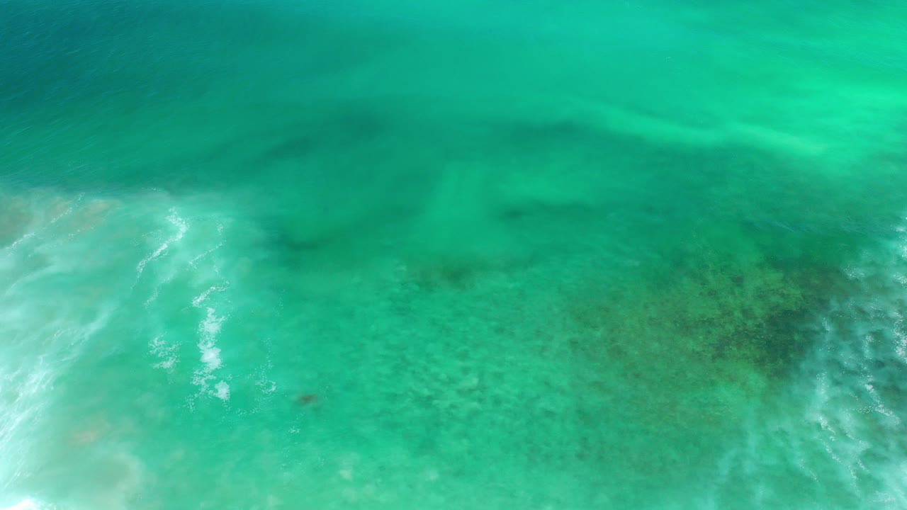 Blue-green underwater ocean view in Los Cabos, Mexico with soft white ripples near the lower left and no visible people.