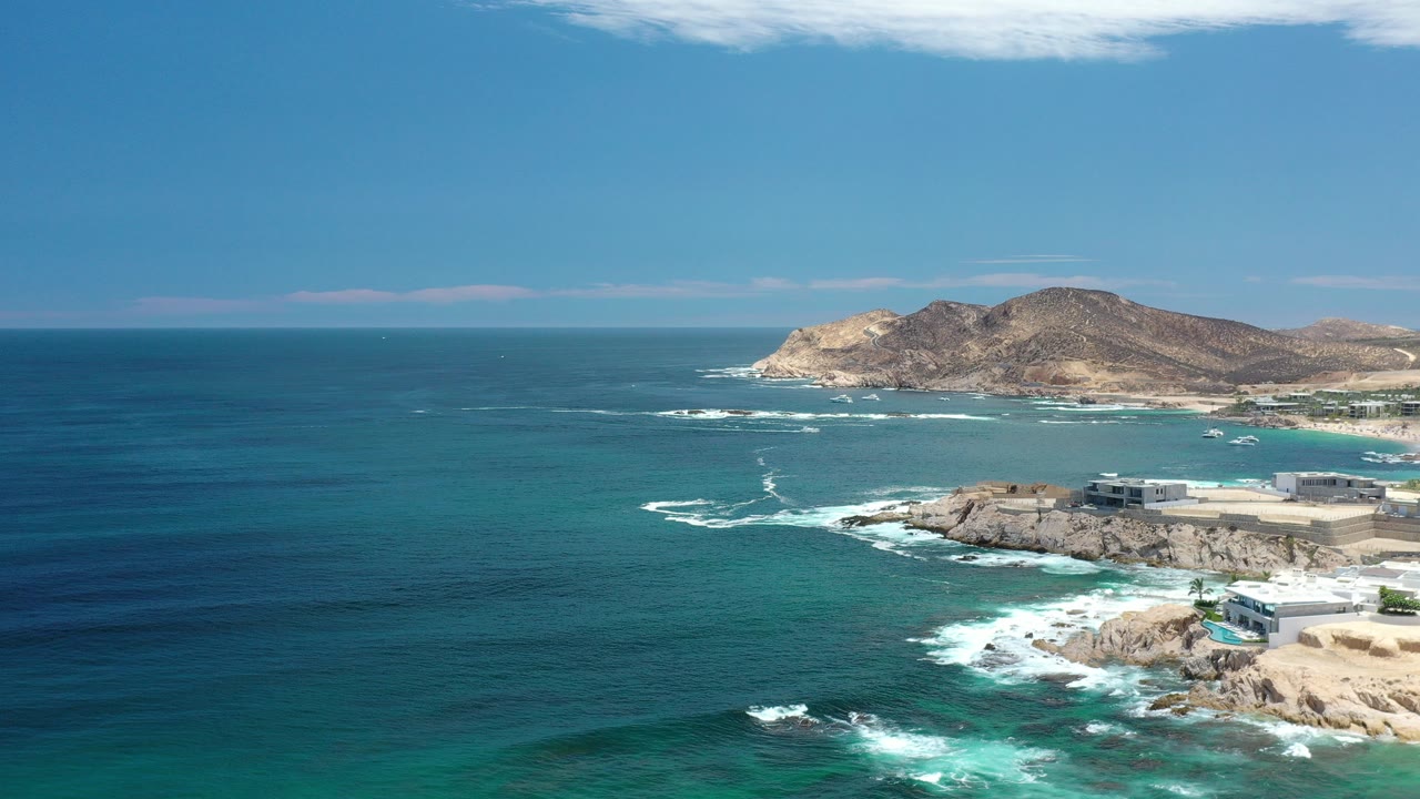 Aerial coastline with blue ocean, rocky shore, and low islands.