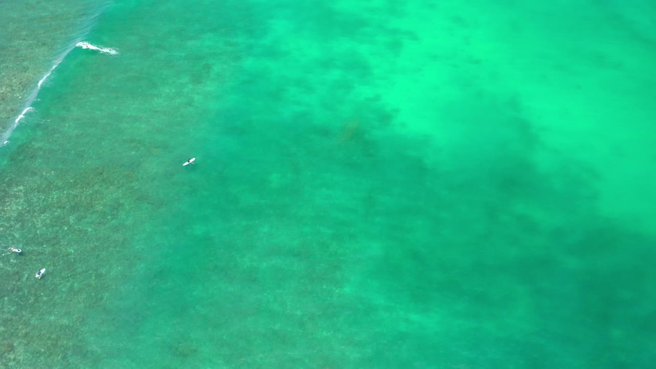 Aerial ocean view with reef texture at left and turquoise water across the frame.