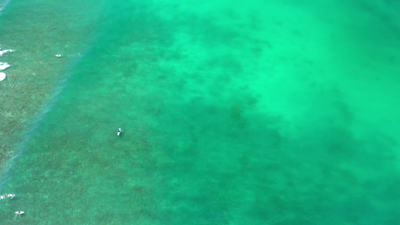 Los Cabos overhead ocean view with the small boat slightly lower in frame, reef color variation on the left, open turquoise water to the right, and no visible people.