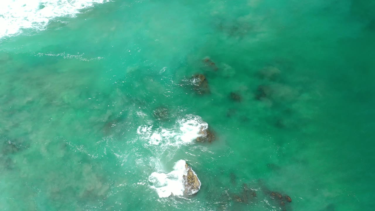 White foam breaking beside rocks in green water