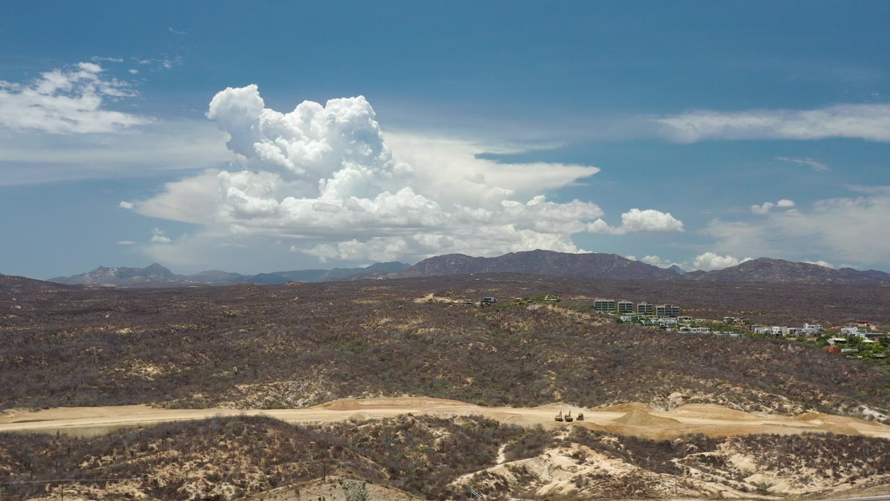 Wide desert terrain under a blue sky with large white clouds