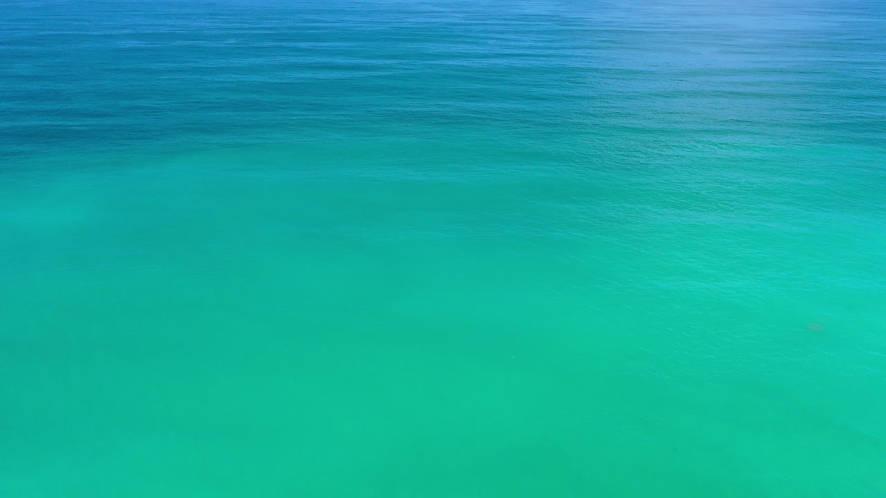 Opening frame of clear turquoise ocean water in Los Cabos, Mexico, with a darker blue band near the top and no visible people.