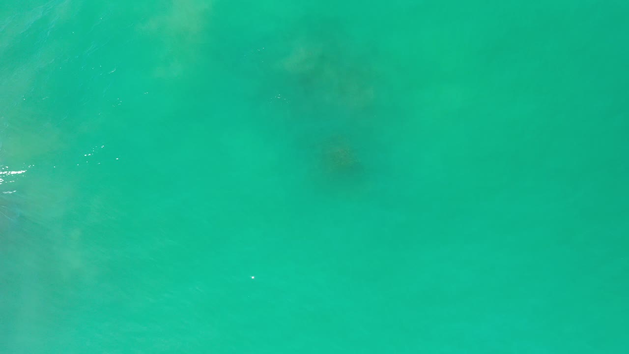 Overhead view of turquoise-green ocean water in Los Cabos, Mexico, with faint underwater patches and no visible people.