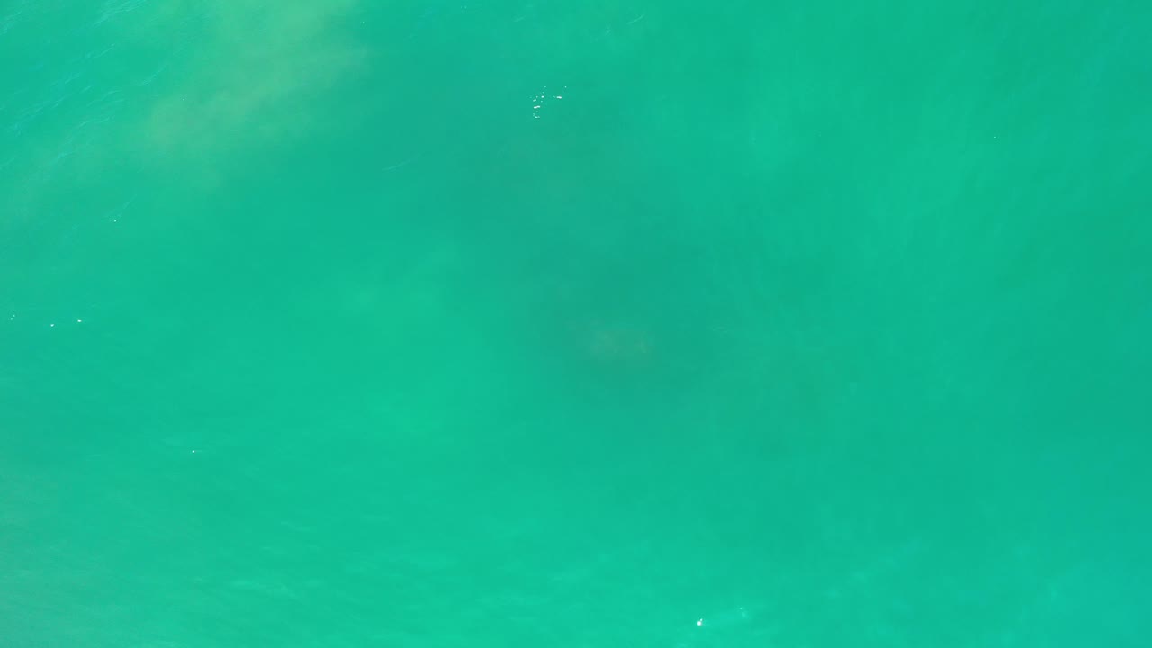 Clear turquoise water with muted rock forms beneath.