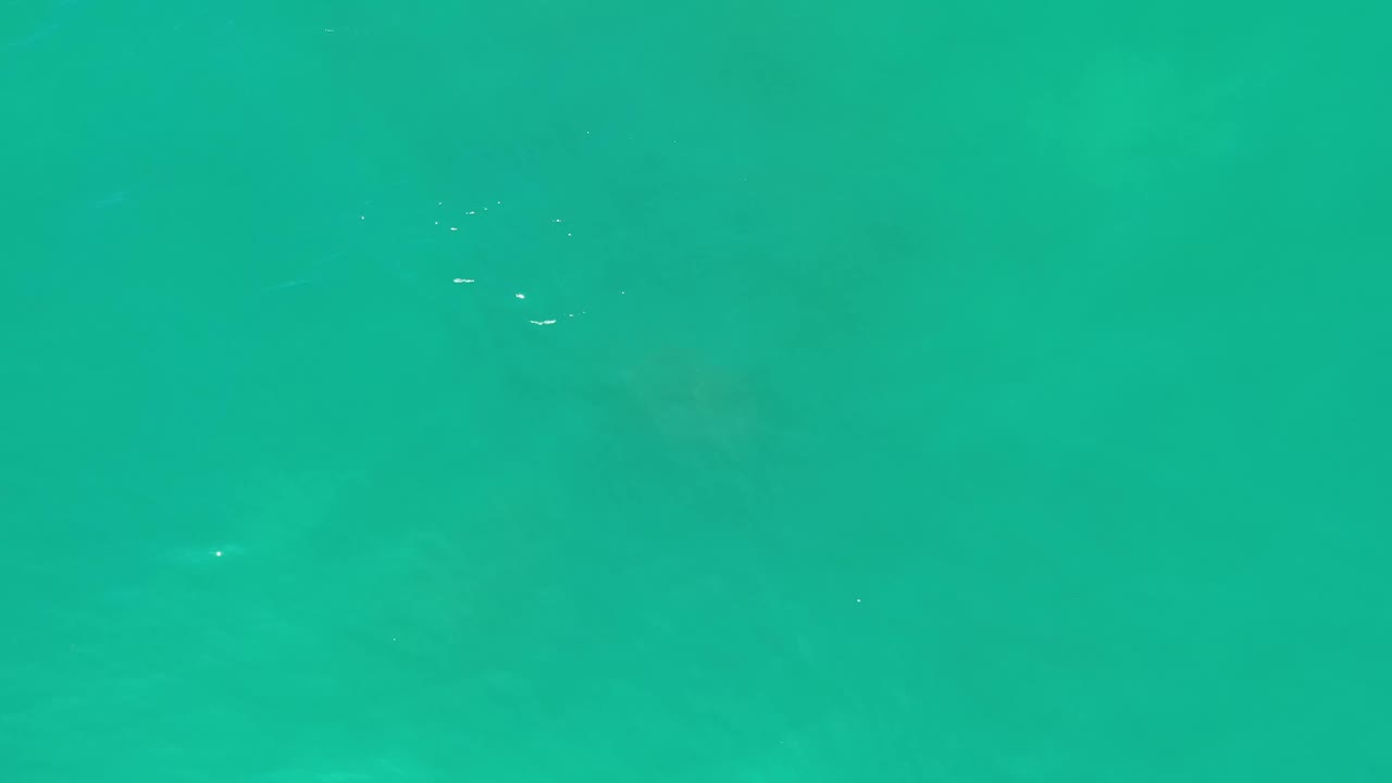 Aerial water frame in Los Cabos, Mexico, showing turquoise shallows, light surface ripples near the upper edge, and no visible people.