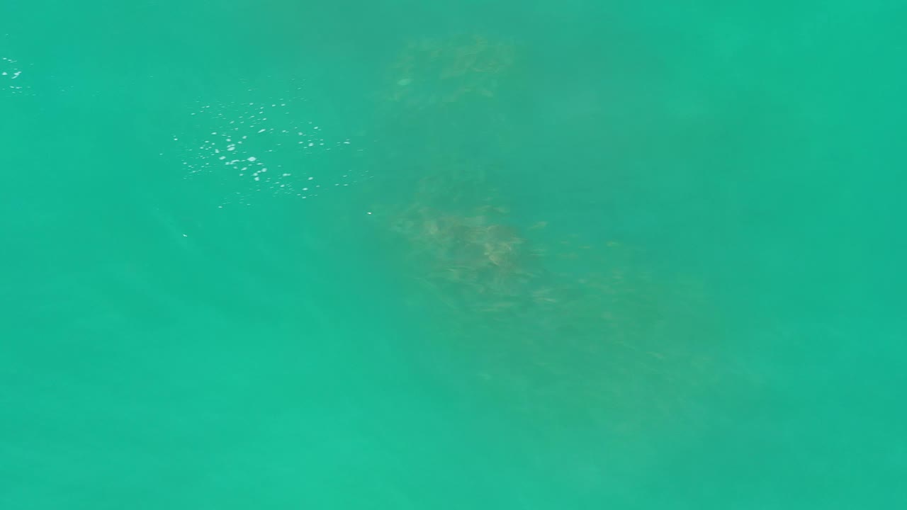 Turquoise ocean surface in Los Cabos, Mexico, with small white glints near the upper frame and no visible people.