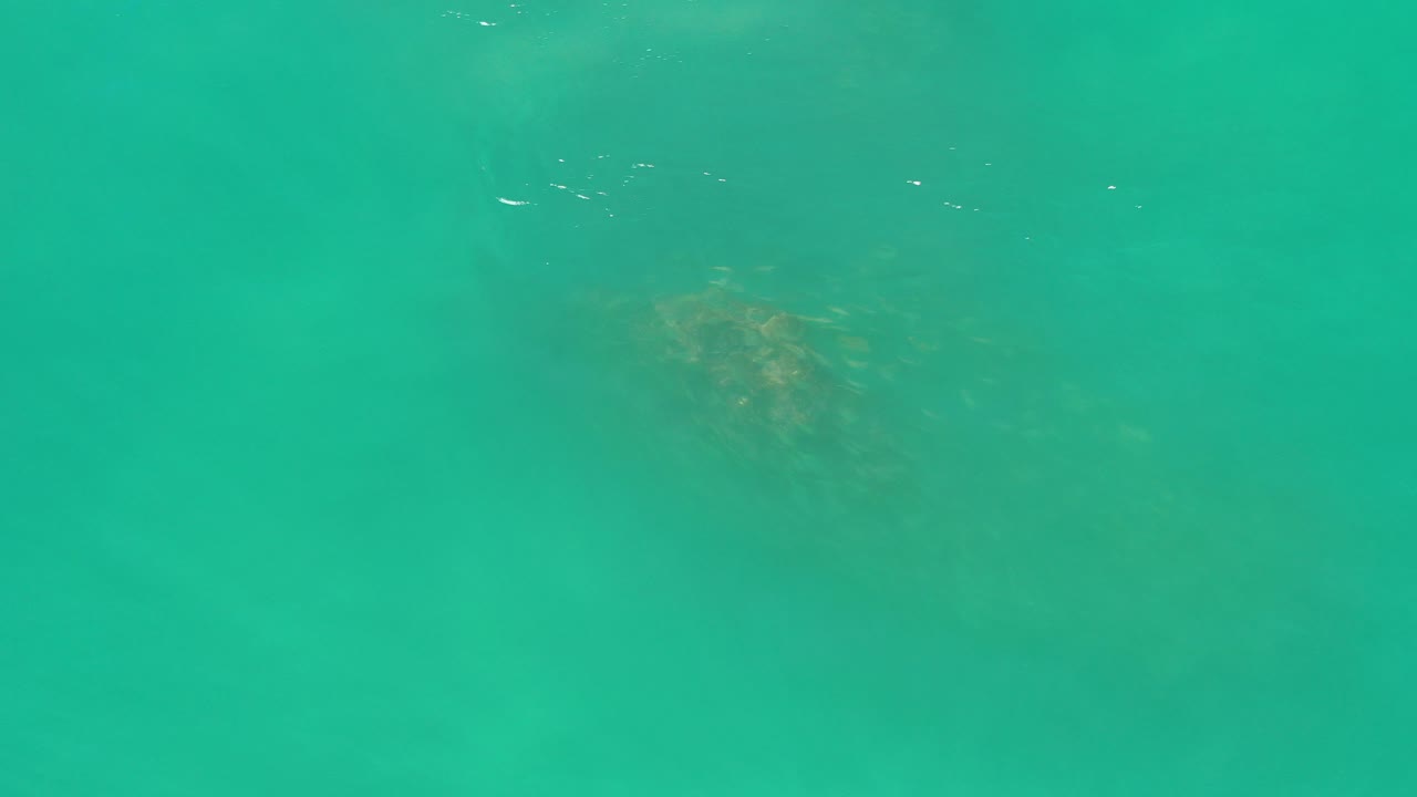 Turquoise ocean water with faint darker patches below the surface