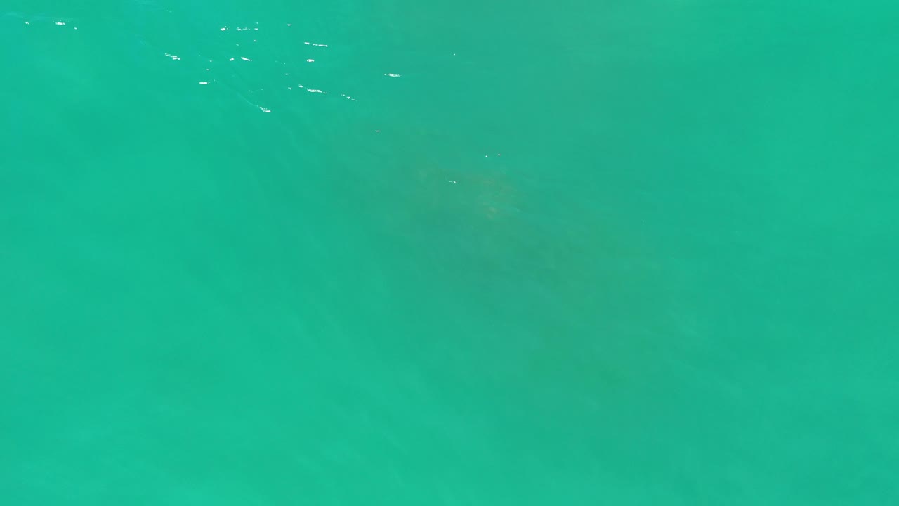 Turquoise-green water with a faint crusty shape beneath it.