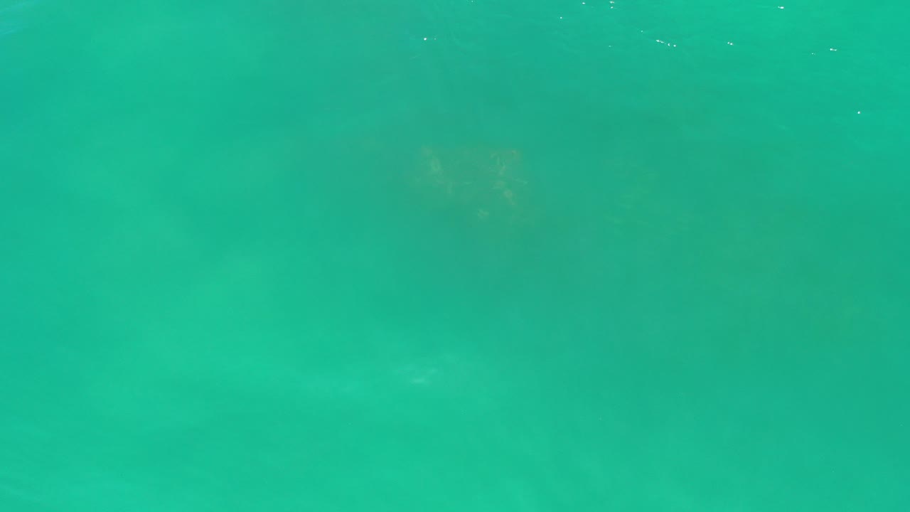 Opening frame of teal green ocean water in Los Cabos, Mexico, with faint surface ripples, darker underwater patches, and no visible people.