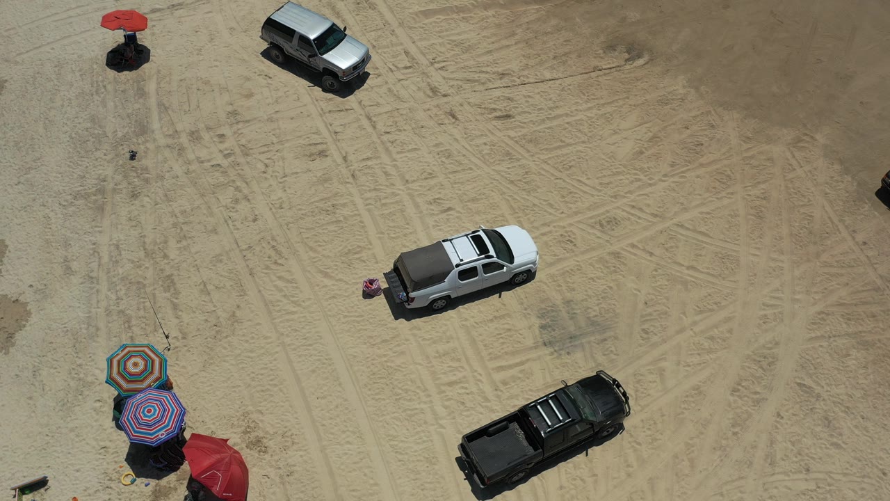 Overhead view of trucks and beach umbrellas on sand