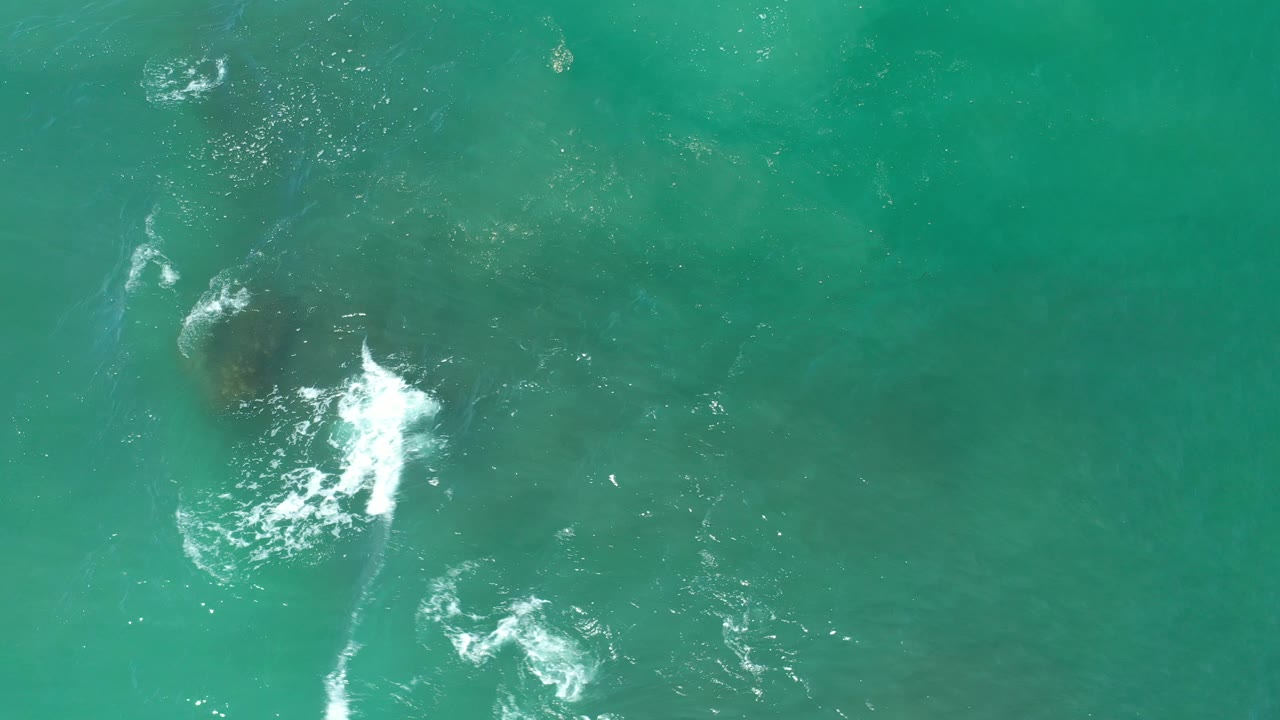 Aerial view of surf streaks above submerged rocks