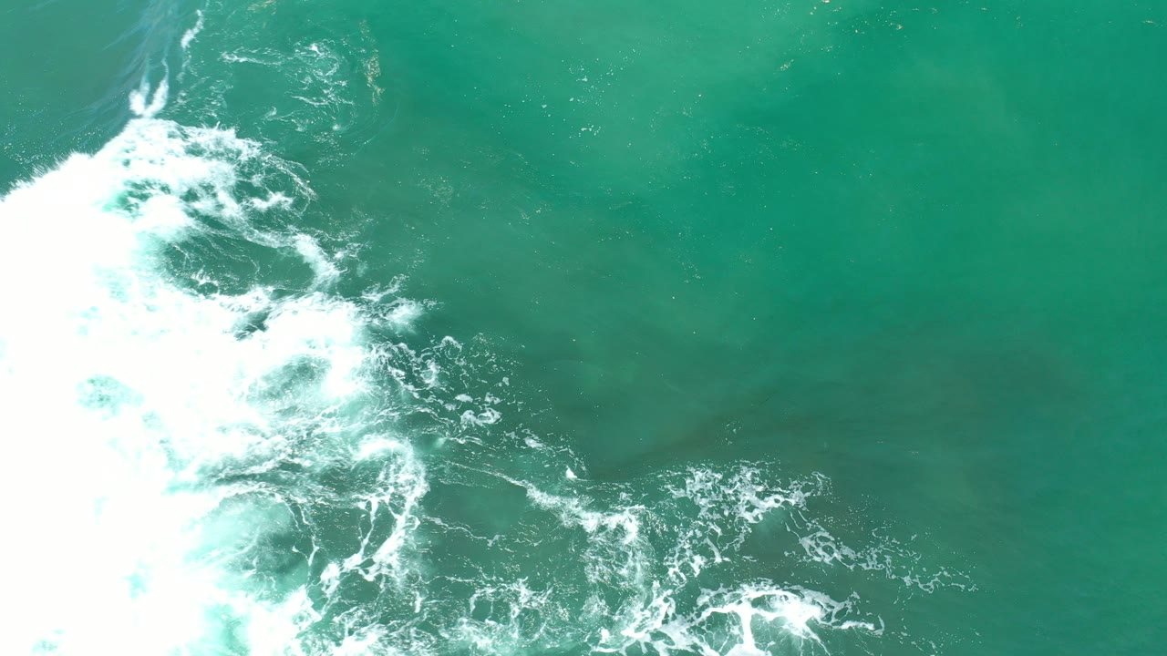 Turquoise water with white surf foam along the left edge.