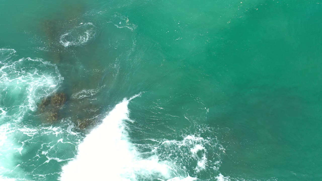 Large white wave break cuts into green ocean water from the lower edge.