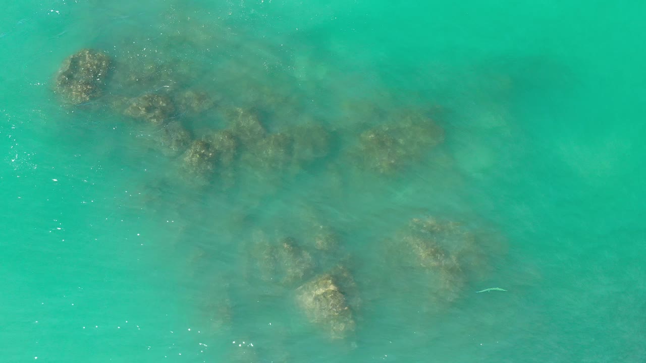 Aerial green water with reef patches softened by ripples.