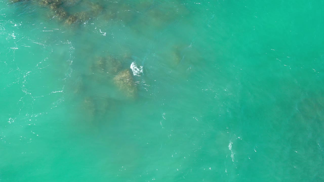 Blue-green sea with rocks visible below the surface.
