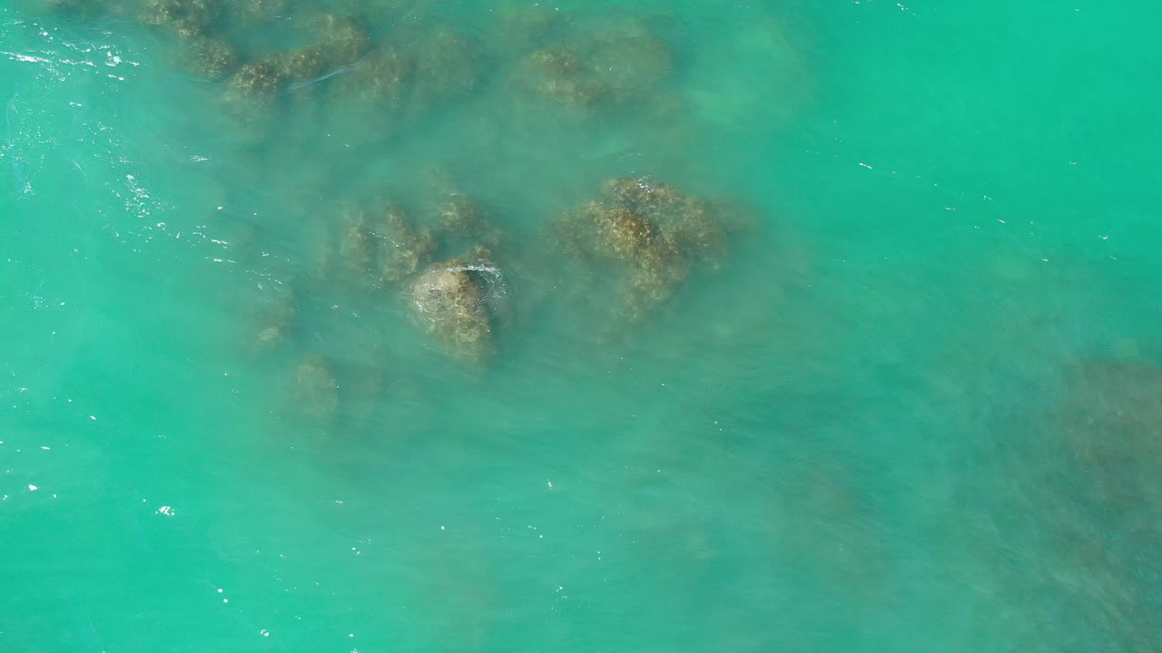 Rocks beneath clear turquoise coastal water.