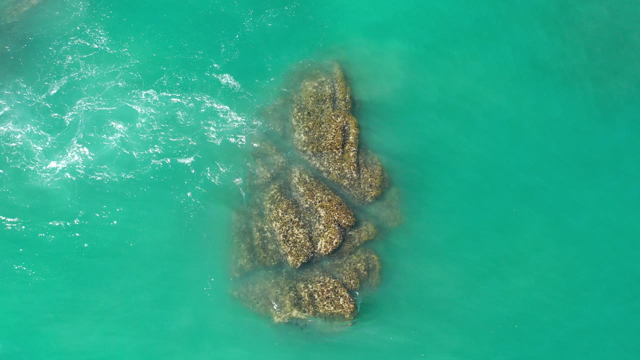 Overhead turquoise water around a cluster of rocks
