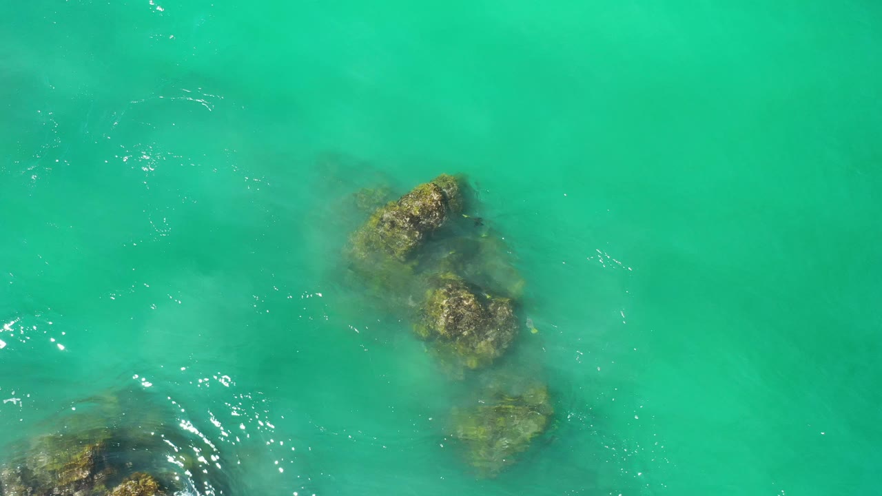 Submerged rock cluster in turquoise-green water with light surface texture.