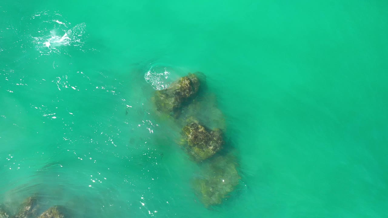 Green-blue water with rocks and a circular splash of foam