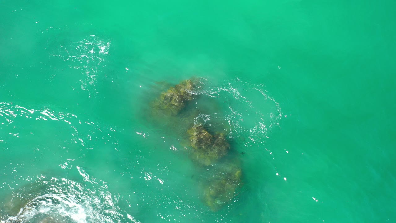 Turquoise ocean water over submerged rock formations.