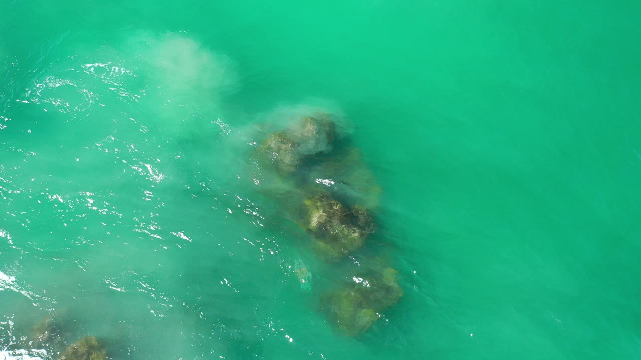 Overhead turquoise water washing over submerged rocks.