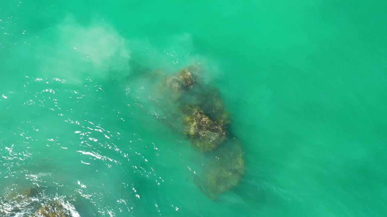 Turquoise water and submerged rocks seen from above.