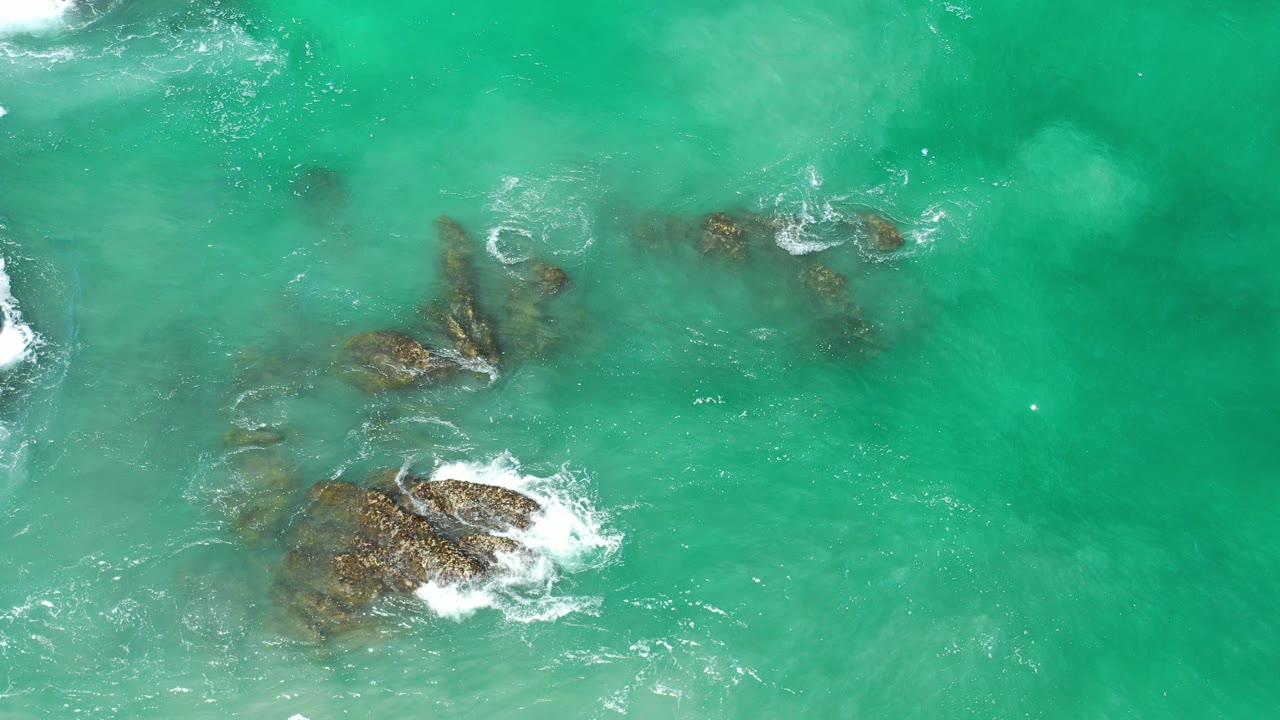 Overhead turquoise water with rocks and white foam.