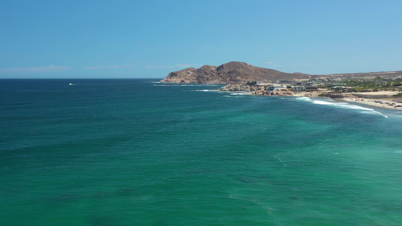 Blue-green ocean foreground with rocky coastal point and beach beyond