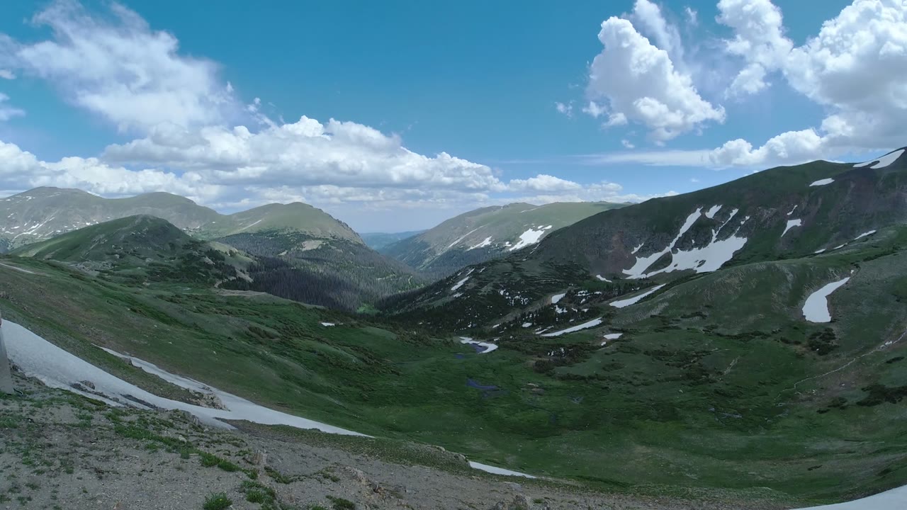 Wide mountain ridges with snow patches under a blue sky
