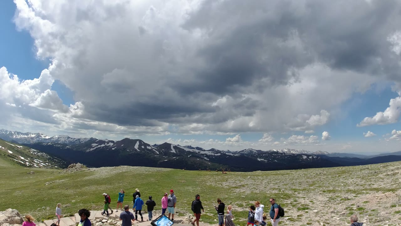 Visitors on a mountain overlook beneath large clouds