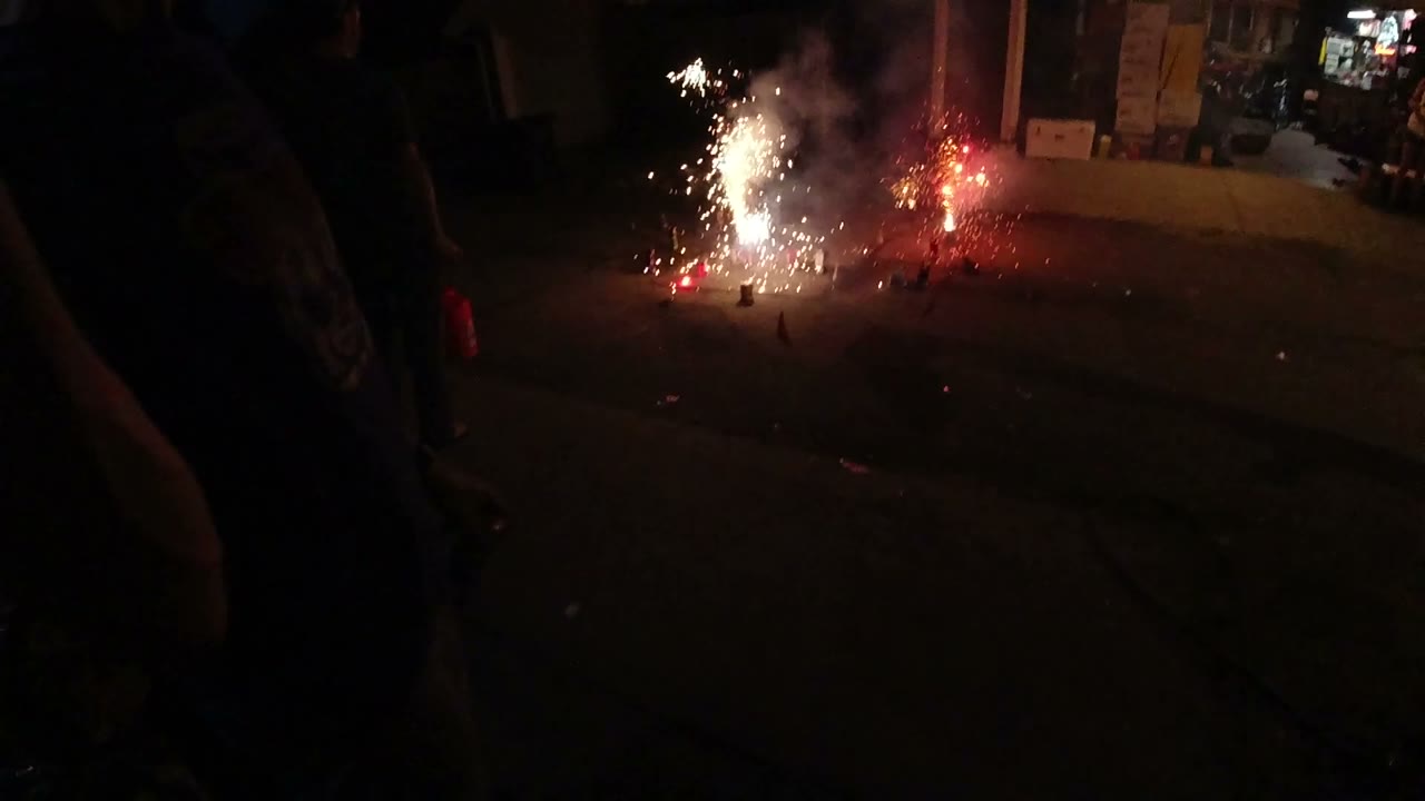 A brighter white fountain burns beside a red flare on the pavement in Denver, with smoke drifting upward and no recognizable faces visible.