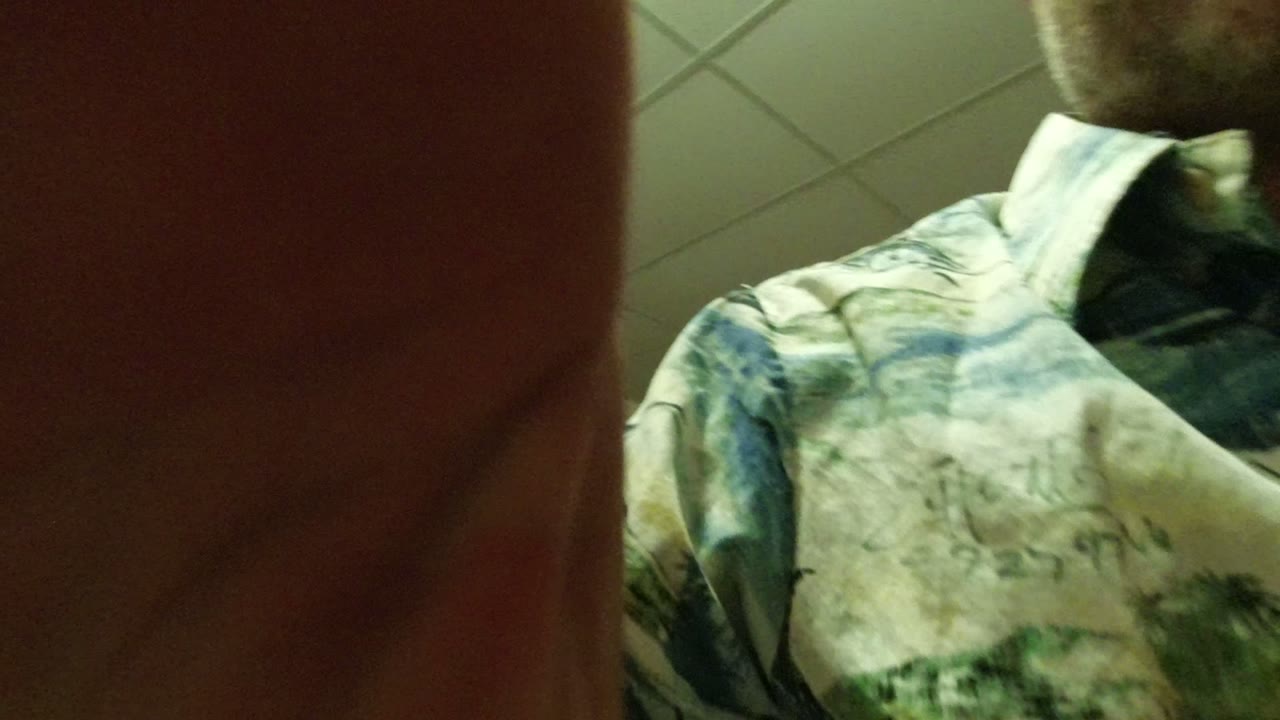 Close obstructed view of a man in a patterned shirt indoors.
