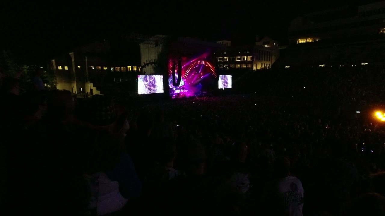 Night crowd with bright stage screens and magenta lights