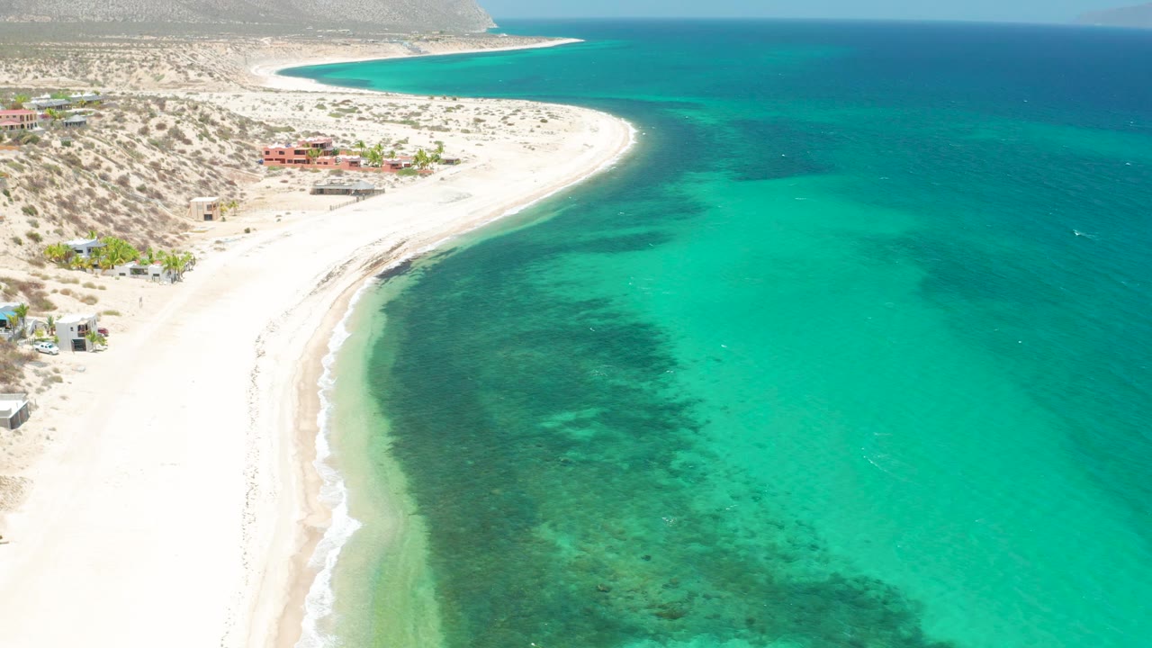 High shoreline view with bright sand and clear blue-green water