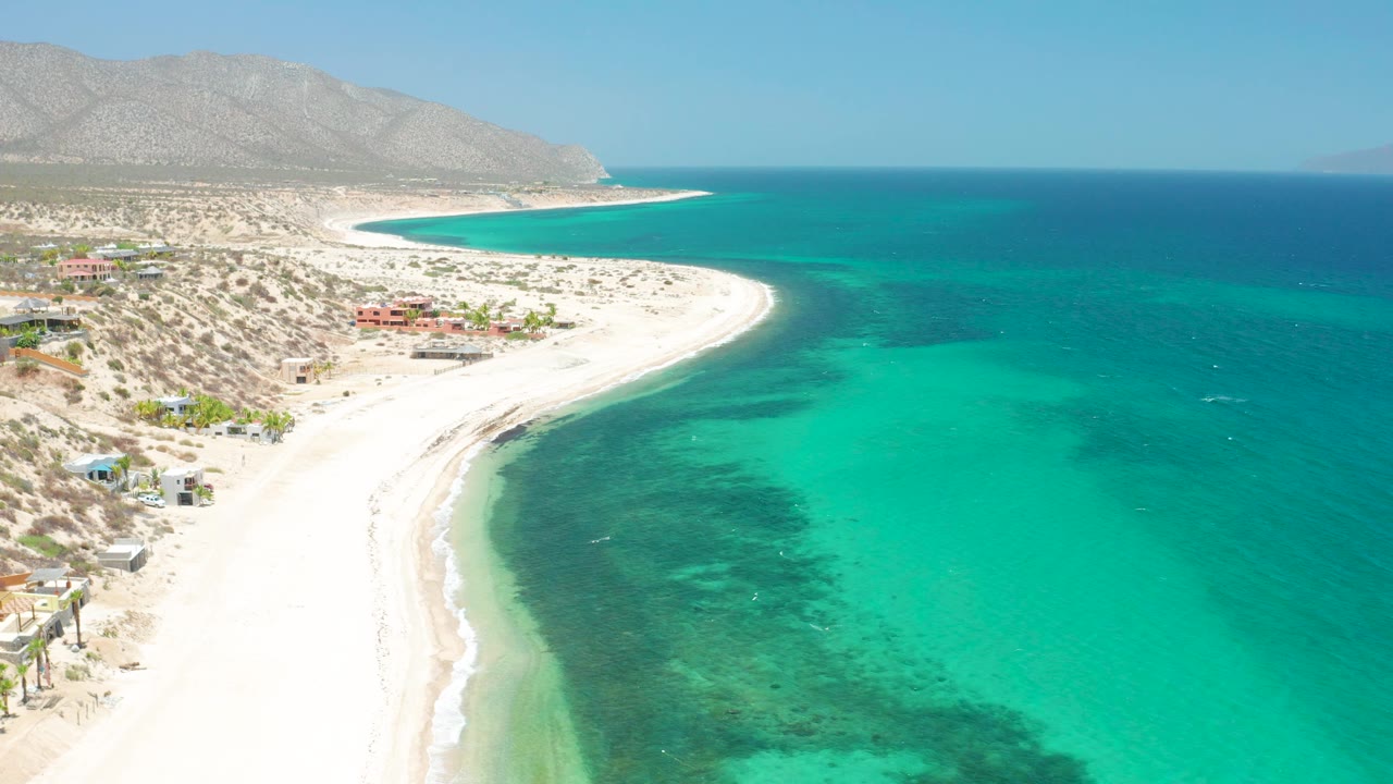 Aerial coastline with white sand beach, desert terrain, and open sea