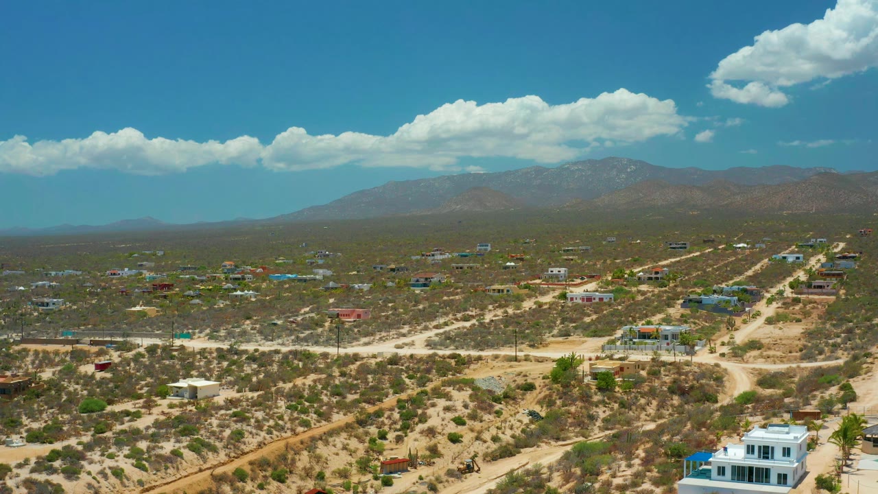 Elevated view of scrubland roads and low buildings beneath mountains