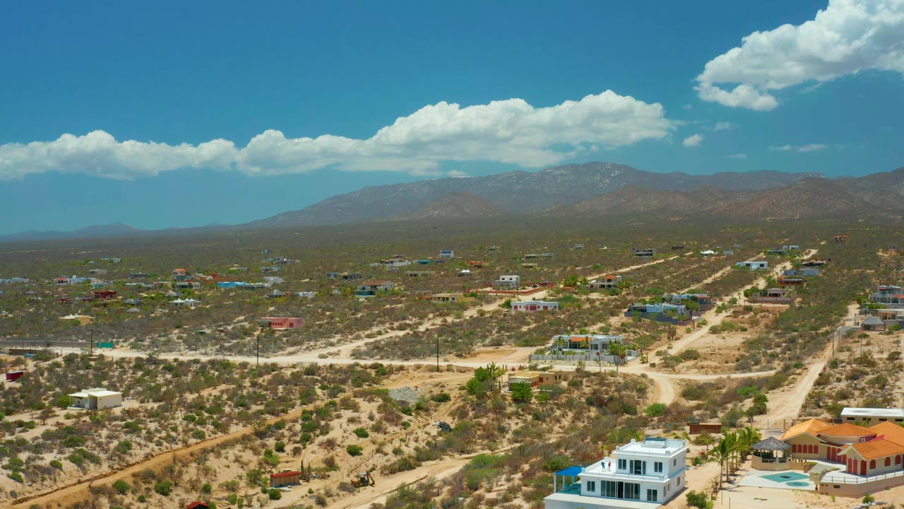 Aerial desert settlement with winding roads and mountain horizon