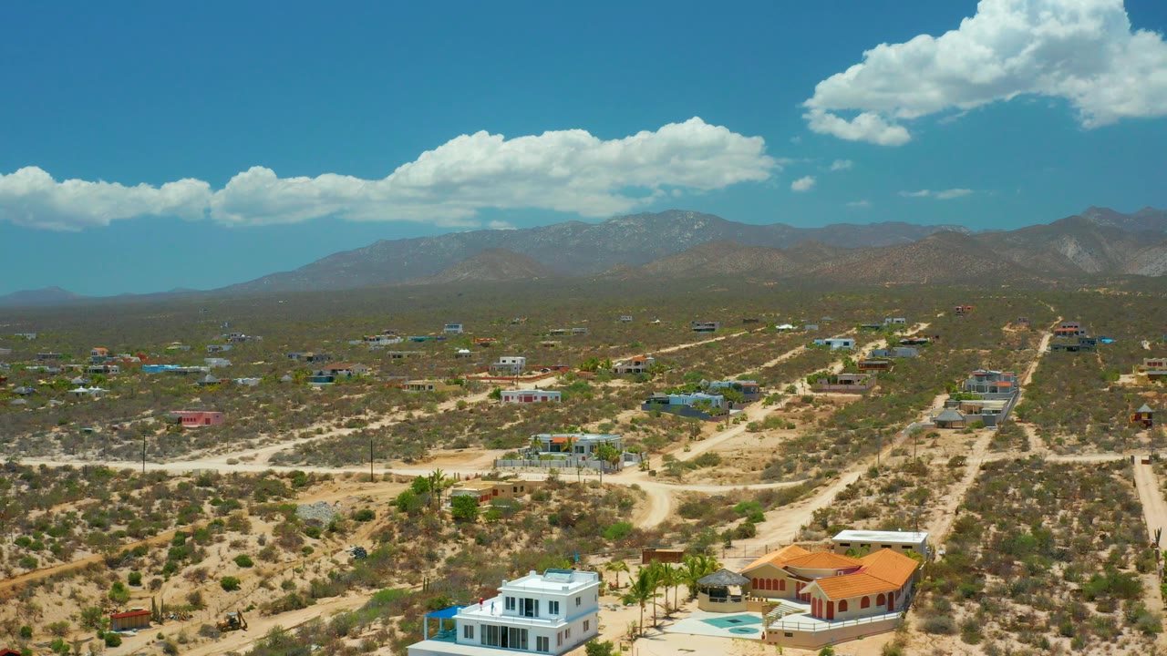 High view of a dry residential area with homes, roads, and mountain skyline.