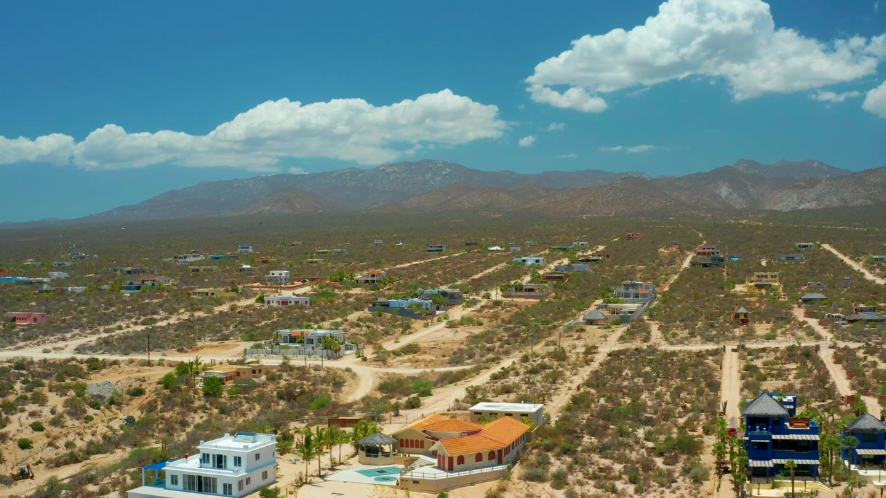 Aerial frame over El Sargento La Ventana, Mexico, showing a sandy road network, isolated homes, low desert brush, a mountain ridge, and no visible people.