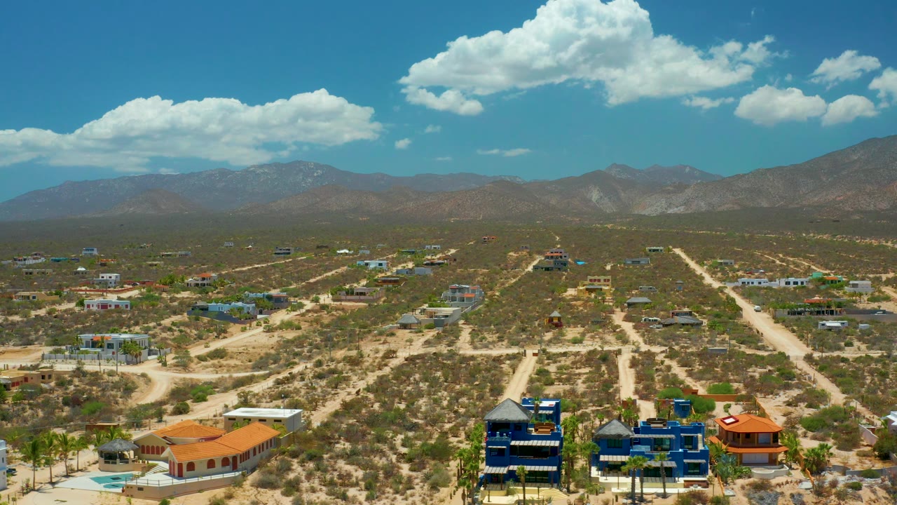 Scattered desert houses and road grid under bright clouds