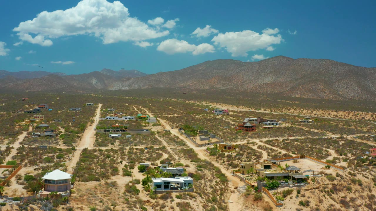 Elevated view over El Sargento La Ventana, Mexico, showing branching dirt tracks, isolated structures, dry vegetation, a broad mountain ridge, and no visible people.