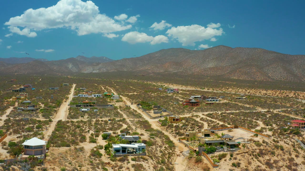 Aerial landscape with desert homes, road corridors, scrub vegetation, and mountains.