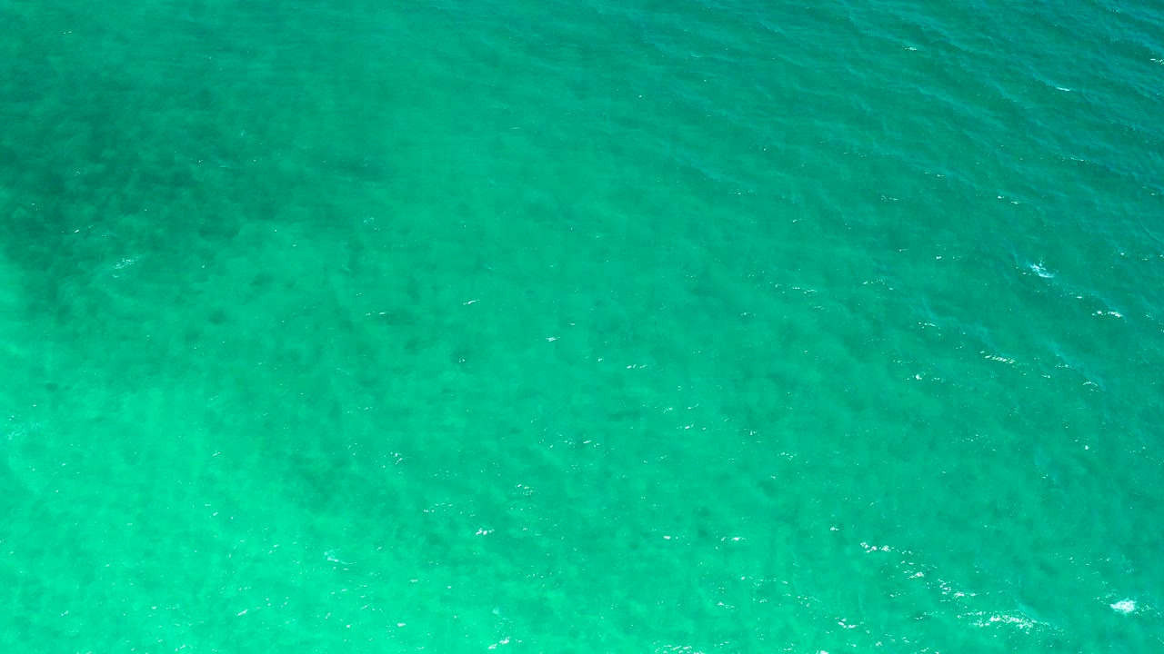Top-down turquoise ocean water with faint darker patches